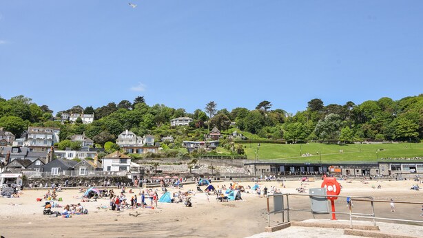 A beach with people, tents, and a lifeguard tower. - The Penthouse @ No 5 (Lyme Regis)
