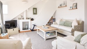 A modern living room with a white sofa, a wooden coffee table, and a television. - The Penthouse @ No 5 (Lyme Regis)