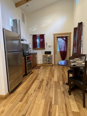 Kitchen area with a refrigerator, microwave, and table for dining.