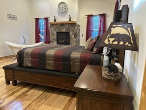 Cozy retreat with a large bed, stone fireplace, and wooden nightstand.
