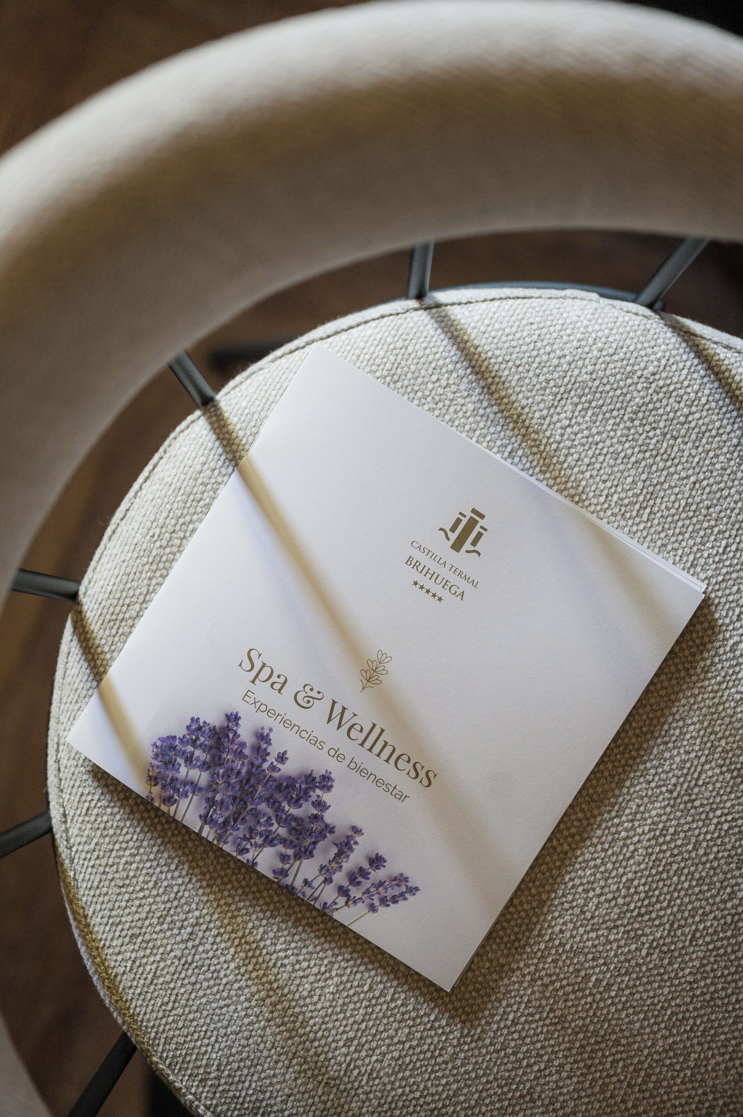 A white card with the text "Spa & Wellness" and "Castilla Terma Brilhega" on a woven chair.
