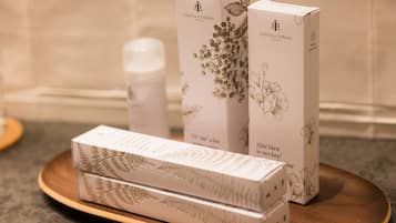A bathroom with a wooden tray holding three boxes of Castilla Termal products, a white towel, and a bottle.