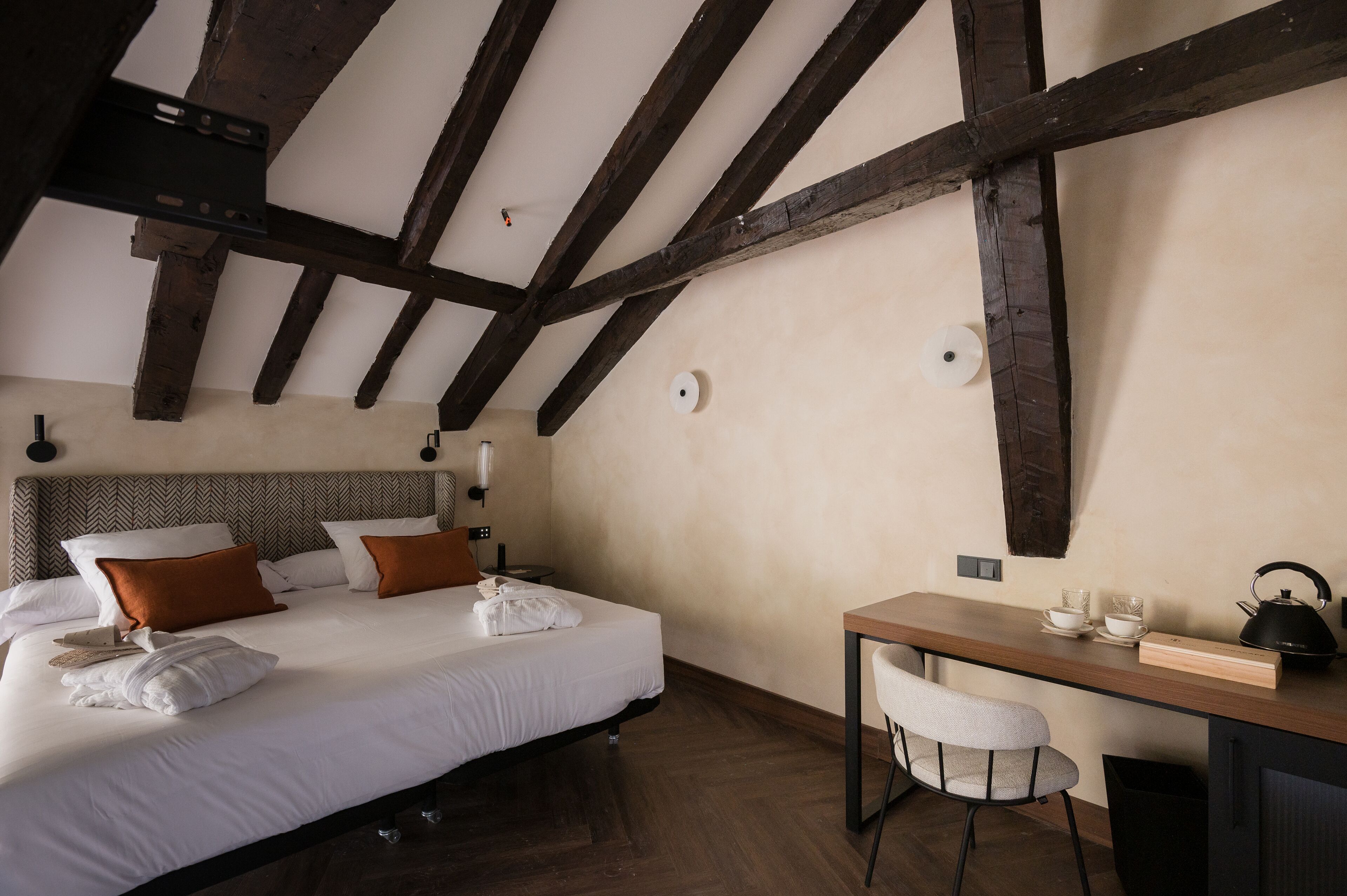Quarto com uma cama grande, uma escrivaninha de madeira e uma cadeira.
