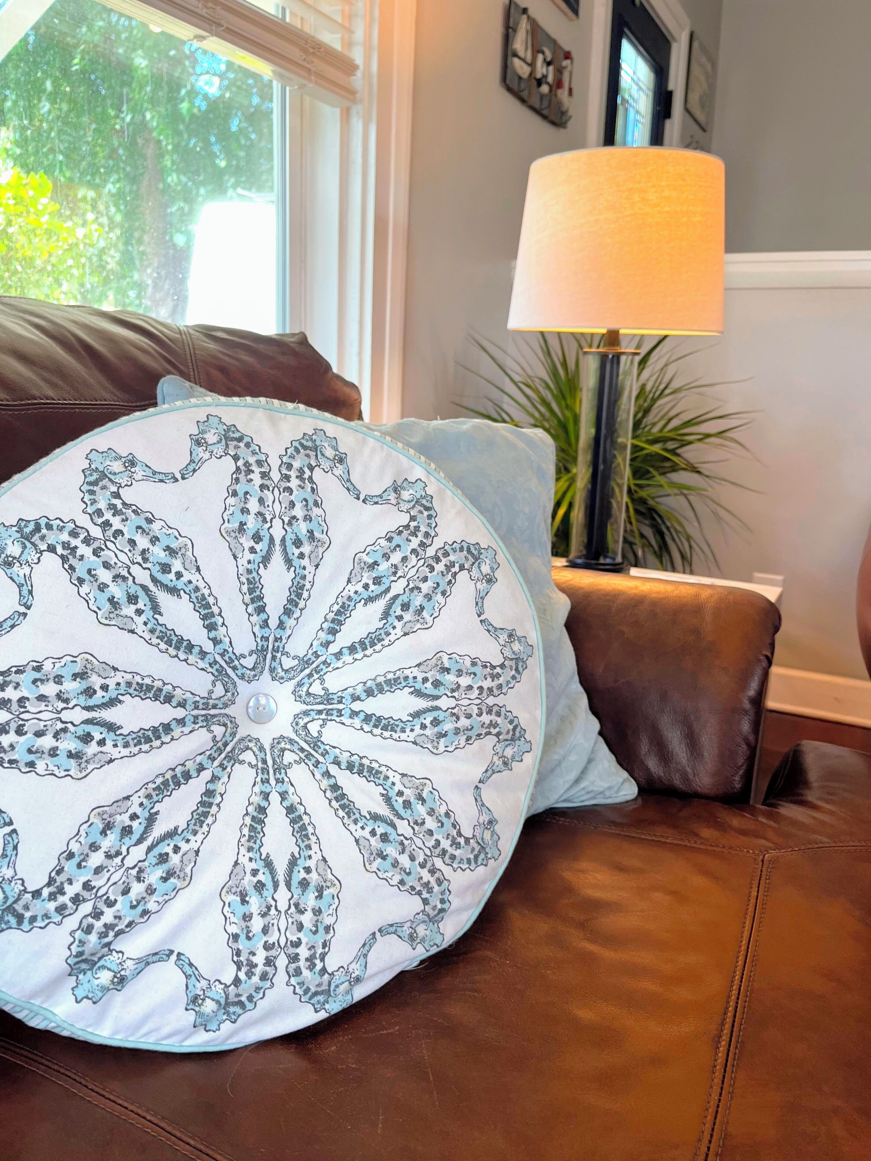 A brown leather sofa with a decorative pillow featuring a blue and white pattern.