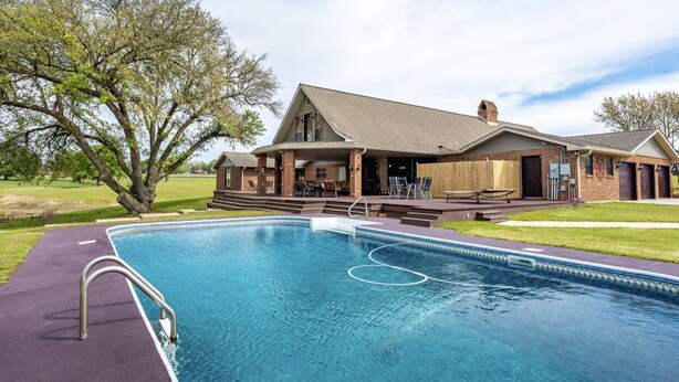 A poolside area with a pool, a covered patio, and a building with a sloped roof. - Angela’s Ashlake Farm Estate Hancock Co. (Poplarville)