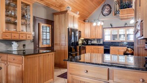 A kitchen with wooden cabinets, a black refrigerator, and a granite countertop. - Angela’s Ashlake Farm Estate Hancock Co. (Poplarville)