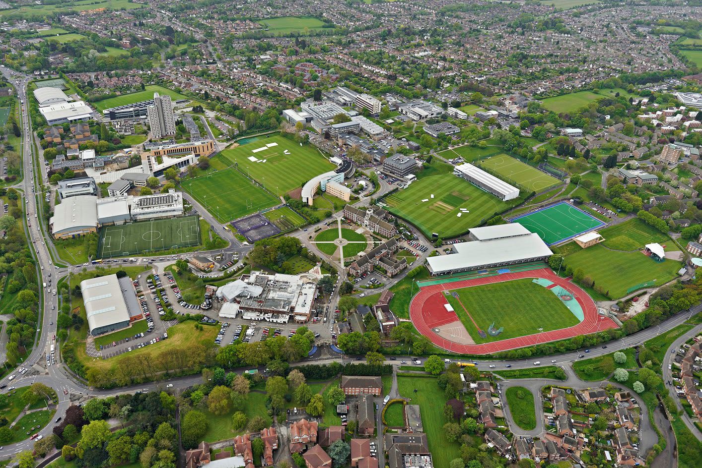 An aerial view of a campus with multiple sports fields, buildings, and roads.
