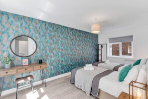 A bedroom with a large bed, a bedside table, a mirror, and a window with a view of a brick wall.