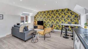 A modern living space with a grey sofa, yellow armchair, and a dining area with a white table and bar stools.