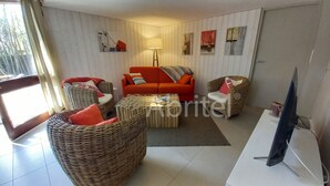 Ein Wohnzimmer mit Korbmöbeln, einem roten Sofa und einem Fernseher.