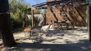 Eine überdachte Terrasse mit Tisch und Stühlen, ein Holzdeck und im Hintergrund ein Holzzaun.