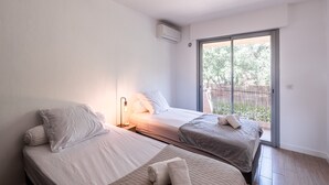 A bedroom with two beds, a sliding glass door to a balcony, and an air conditioning unit on the wall. - Apartment 4P 97M2 Sea view city center (Porto-Vecchio)