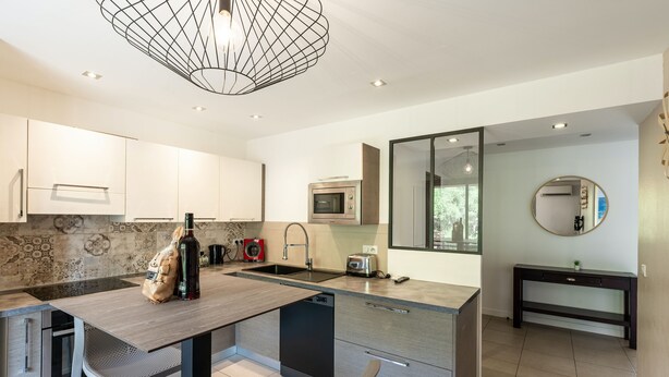 A modern kitchen with a central island, built-in appliances, and a dining area with chairs. - Apartment 4P 97M2 Sea view city center (Porto-Vecchio)