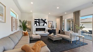 Un salon moderne doté d’une cheminée, d’un canapé, d’une table basse et d’un coin repas avec des sièges extérieurs.