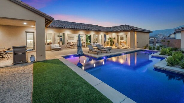 Une maison moderne dotée d’une piscine, d’un espace extérieur aménagé et d’une pelouse bien entretenue.
