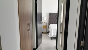 A hotel hallway with a bed, bedside table, and a lamp.