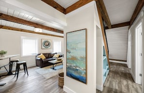 A spacious living room with a wooden ceiling, a large painting, a sofa, and a dining area. - Minutes from the Beach!<br>A-Frame at The Point (Pensacola)