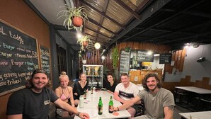 Un grupo de personas sentadas alrededor de una mesa en un restaurante, con un menú en la pared.