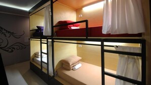 Habitación con literas, una ventana, decoración en la pared y una cortina.