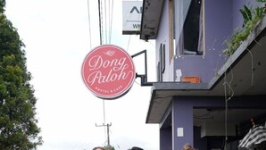 Tres personas de pie frente a un hostal con un letrero que dice "Dong Paloh Hostel & Cafe".