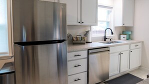 Een moderne keuken met roestvrijstalen apparatuur, witte kastjes en een raam dat voor natuurlijk licht zorgt.