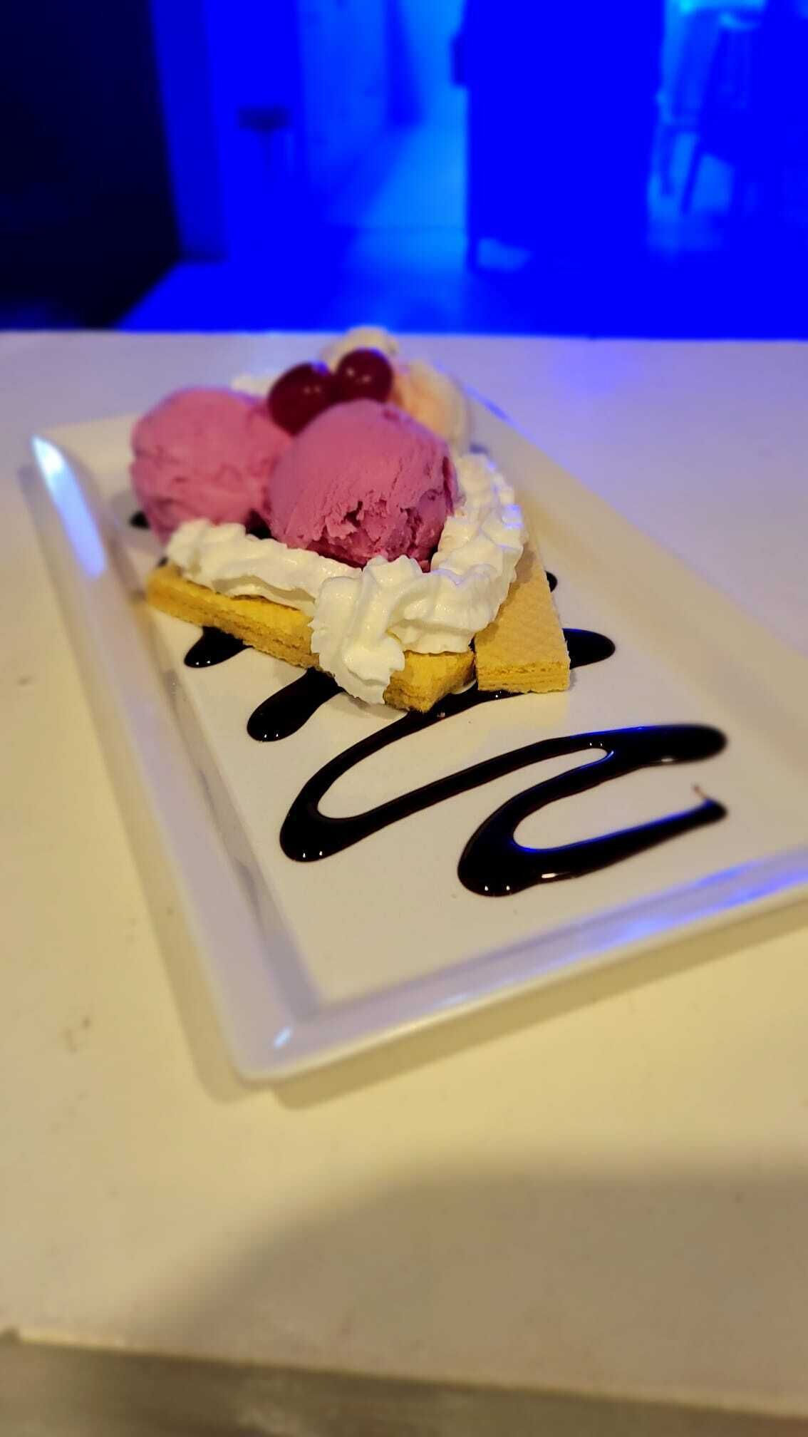A dessert plate with ice cream, whipped cream, and chocolate sauce.