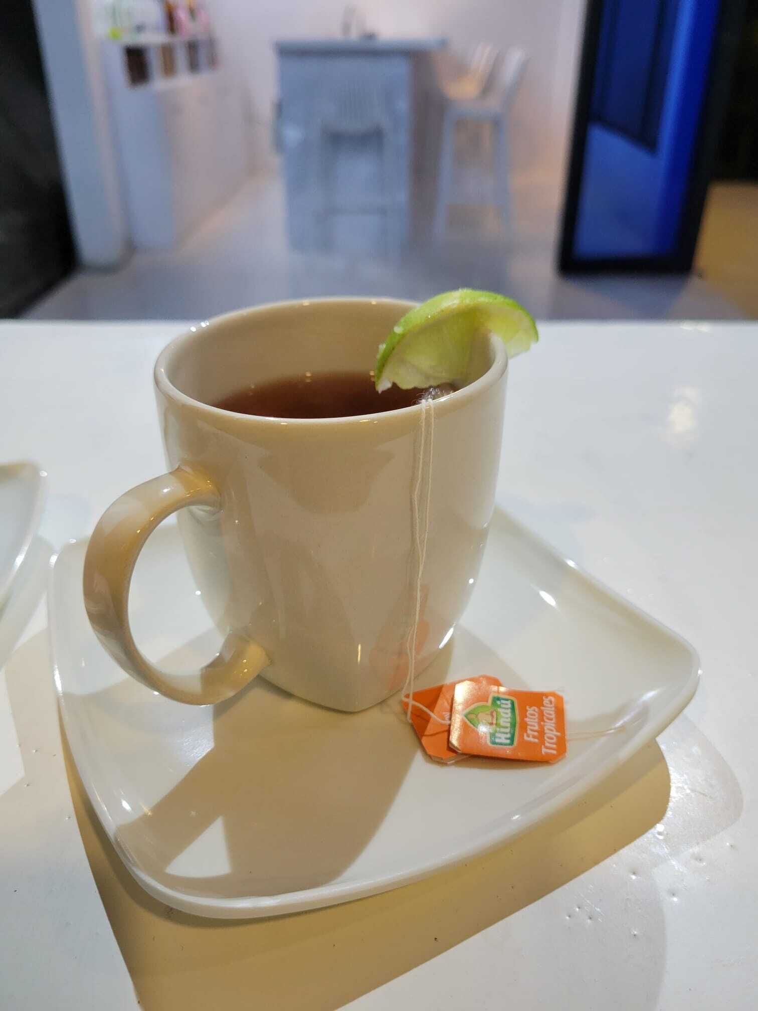 Uma chávena de chá com uma fatia de limão num pires, colocada sobre uma mesa branca.