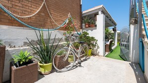 A bicycle parked next to a brick wall, potted plants, and a gated entrance. - Apartment 'Casa Nora' with Private Terrace, Wi-Fi and Air Conditioning (Calasetta)
