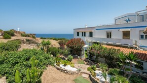 A coastal building with a cross, a garden with various plants, and a view of the sea. - Apartment 'Casa Nora' with Private Terrace, Wi-Fi and Air Conditioning (Calasetta)