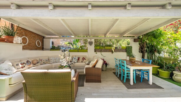 A covered outdoor seating area with a sofa, wicker chairs, and a dining table. - Apartment 'Casa Nora' with Private Terrace, Wi-Fi and Air Conditioning (Calasetta)