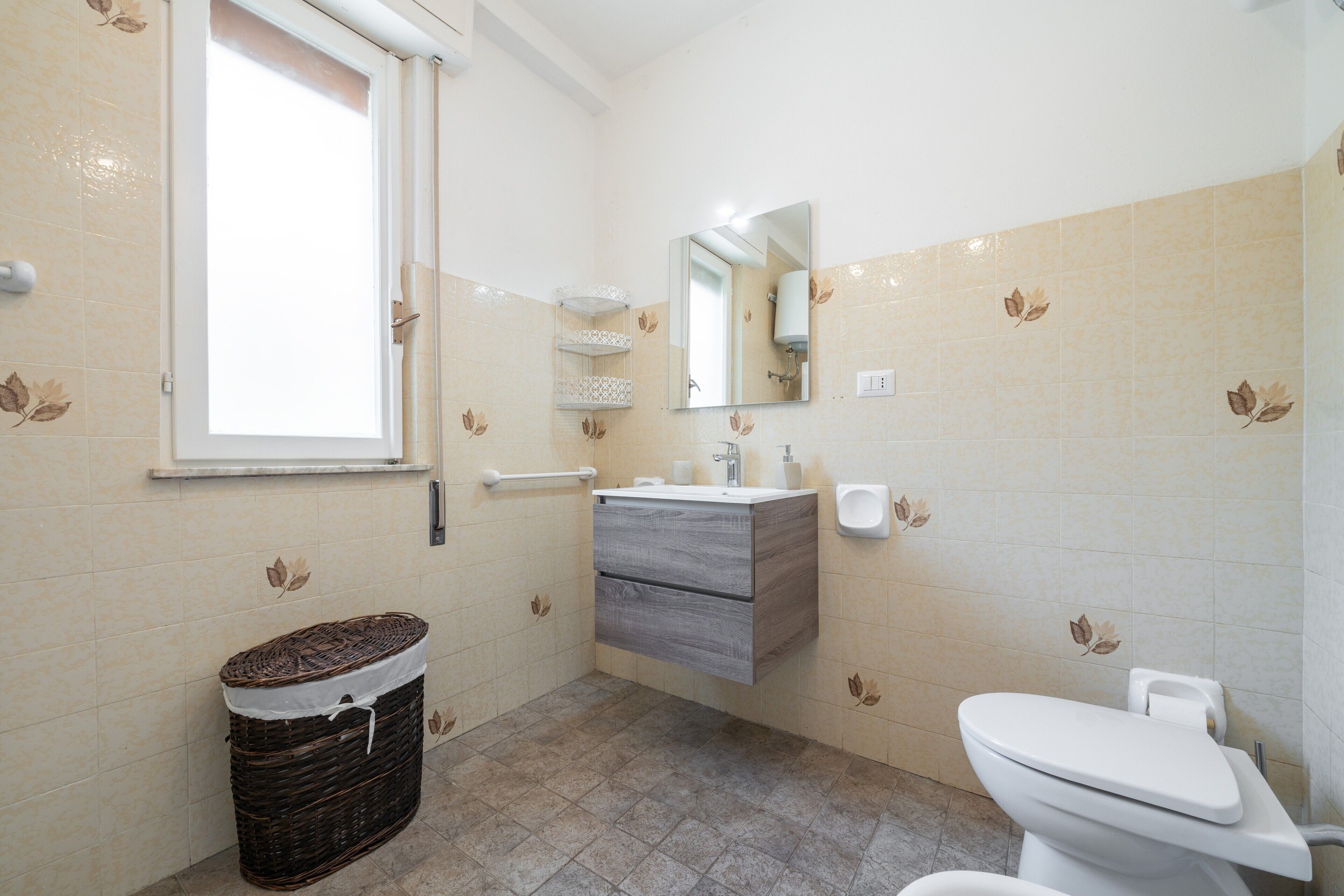 Ein Badezimmer mit Toilette, Waschbecken, Spiegel und Fenster.