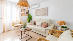A living room with a sofa, two wicker chairs, a coffee table, a hanging light fixture, and a wall-mounted air conditioner. - Holiday Home "El Pinito Moraira" with Private Terraces, Private Pool & Wi-Fi (Moraira)
