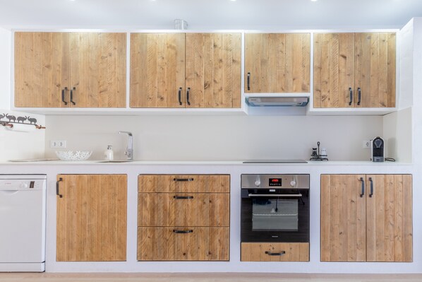 A modern kitchen with wooden cabinets, a dishwasher, an oven, and a coffee maker.