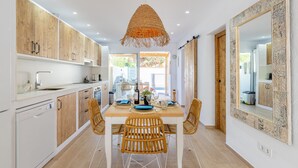 A modern kitchen with wooden cabinets, a dining table with chairs, and a large mirror. - Holiday Home "El Pinito Moraira" with Private Terraces, Private Pool & Wi-Fi (Moraira)
