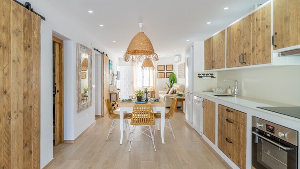 A modern kitchen with wooden cabinets, a dining area with wicker chairs, and a large pendant light. - Holiday Home "El Pinito Moraira" with Private Terraces, Private Pool & Wi-Fi (Moraira)