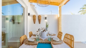 An outdoor dining area with a table set for six, surrounded by wicker chairs, a woven placemat, and a central decorative pot. - Holiday Home "El Pinito Moraira" with Private Terraces, Private Pool & Wi-Fi (Moraira)