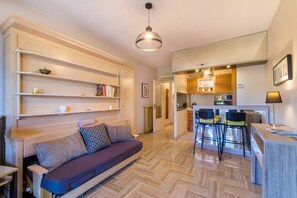 A compact living space with a sofa, kitchenette, and a dining area. - Studio "Riviera de Bahia" with Pool in a Green Park, Steps from the Beach (Villeneuve-Loubet)
