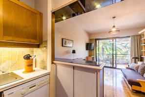 A kitchen with a countertop, a sink, and a dining area with a sofa and a table.