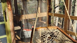 Eine Holzterrasse mit einer am Holzbalken befestigten Rope-Swing-Schaukel.