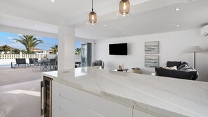 Une cuisine moderne dotée d’un plan de travail en marbre, de luminaires suspendus et offrant une vue sur la terrasse extérieure.