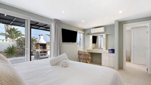 Une chambre d’hôtel équipée d’un lit, d’une télévision, d’une salle de bain et d’un balcon avec un barbecue et des plantes.