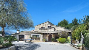 A stone building with a tiled roof, a balcony, and a sign that reads "Hotel Grigorio".