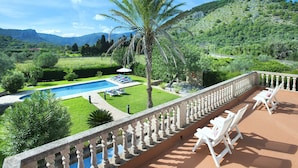 A pool with lounge chairs, a palm tree, and a view of a mountainous landscape. - Villa Busqueroles by Villa Plus (Pollença)