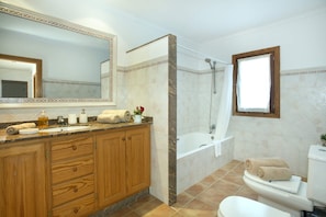 Un baño con tocador de madera, un espejo grande, una bañera y un inodoro.