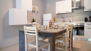 A modern kitchen with white cabinetry, a wooden dining table, and chairs. - Apartment "Il Sole Di Calde Lago Maggiore 504" with Lake View, Balcony & Wi-Fi (castelveccana)