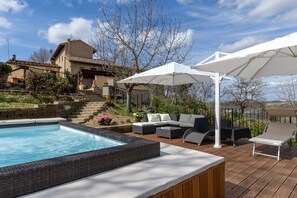 A swimming pool with a hot tub, outdoor seating, and a view of a hillside house. - Holiday Home 'La Loggia di Giulia' with Private Terrace, Hot Tub and Garden (San Gimignano)