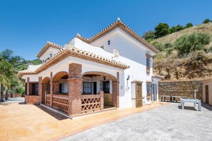 Une maison à deux étages dotée d’un patio, d’arcs en briques et d’un mur en pierre.