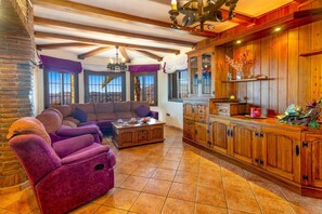 A spacious living room with a large sofa, a wooden cabinet, and a dining area with a table. - Villa Biznaga by Villa Plus (Valtocado)