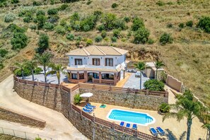 A two-story house with a swimming pool, surrounded by a stone wall and palm trees. - Villa Biznaga by Villa Plus (Valtocado)
