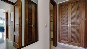 A hallway with wooden doors and a mirror reflecting the space. - Apartment Costalita with Sea View, Terrace, Shared Pool & Wi-Fi (Estepona)